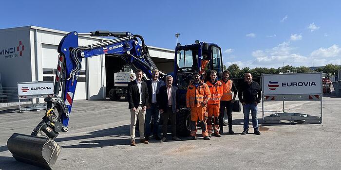 Bagger mit Auszubildenden im Vordergrund 