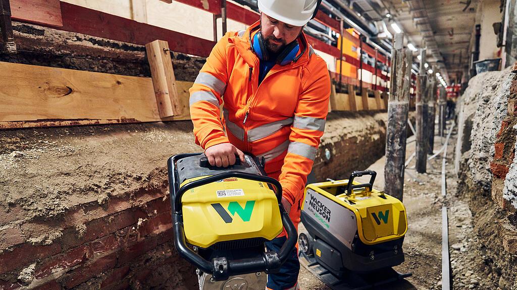 man changes battery from battery powered rammer from wacker neuson at construction site