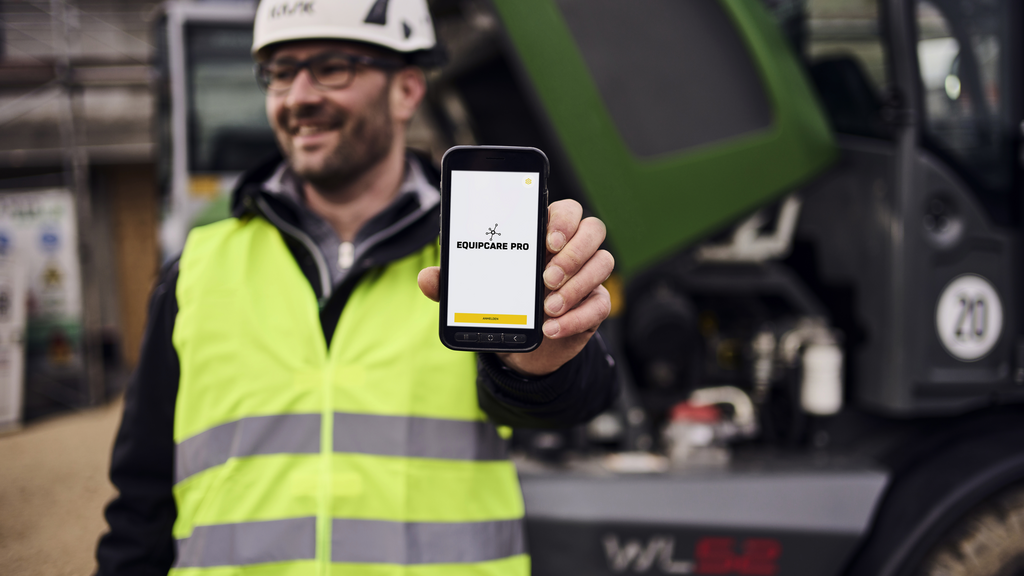 Customer holding smartphone with construction software EquipCare Pro in the camera.