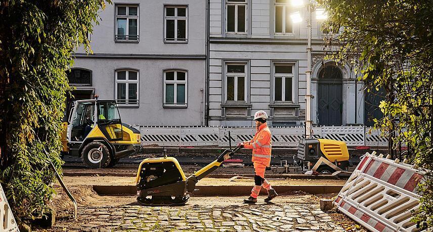Man working with dumper on road with old expensive houses in the background
