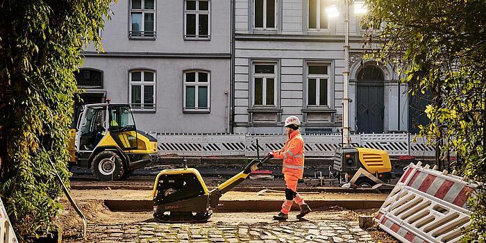 Mann arbeitet an der Straße mit alten, teuren Häusern im Hintergrund