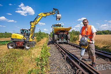 Während der Gleisstopfer BH55rw präzise Stopf- und Unterfütterungsarbeiten im Gleisbett übernimmt, sorgen der Zwei-Wege-Dumper DV90 und der Mobilbagger EW100 für den effizienten Materialtransport auf der Schiene.