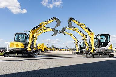 yellow excavators standing side by side and building an arch with their excavator arms