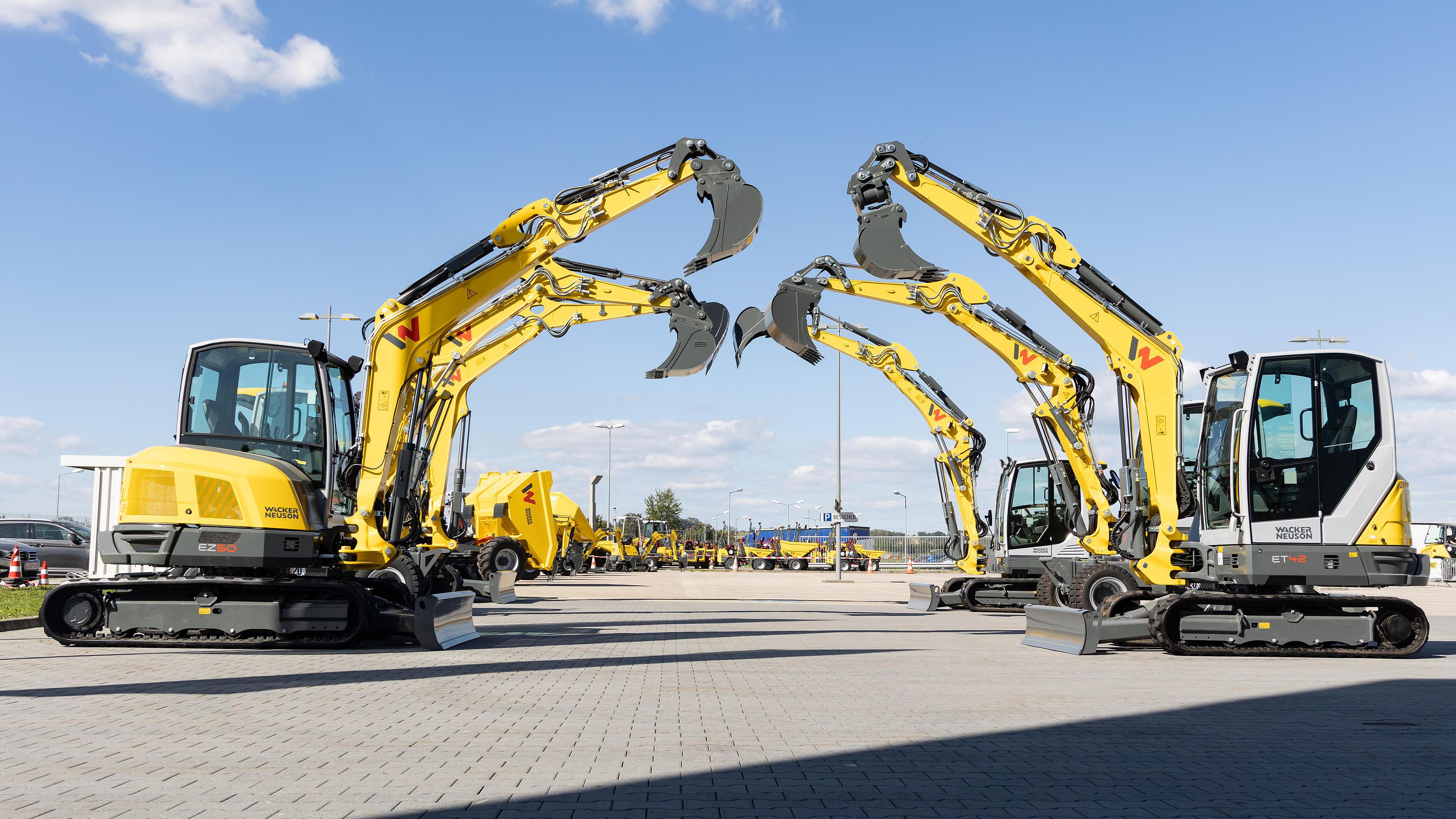 yellow excavators standing side by side and building an arch with their excavator arms