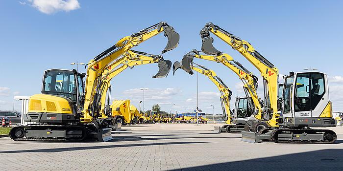 yellow excavators standing side by side and building an arch with their excavator arms