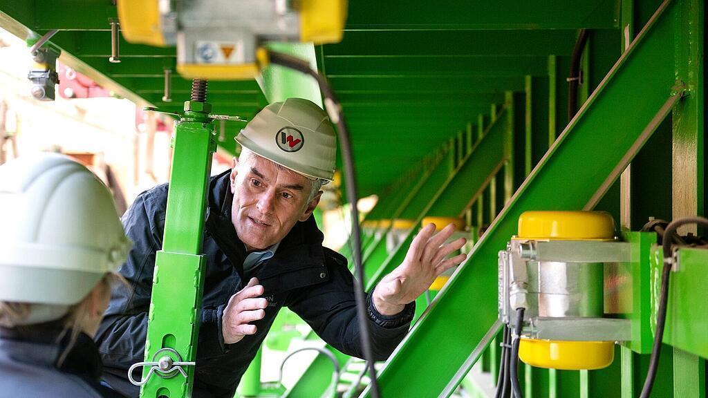 Wacker Neuson Mitarbeiter steht vor Außenrüttler und erklärt diesen.