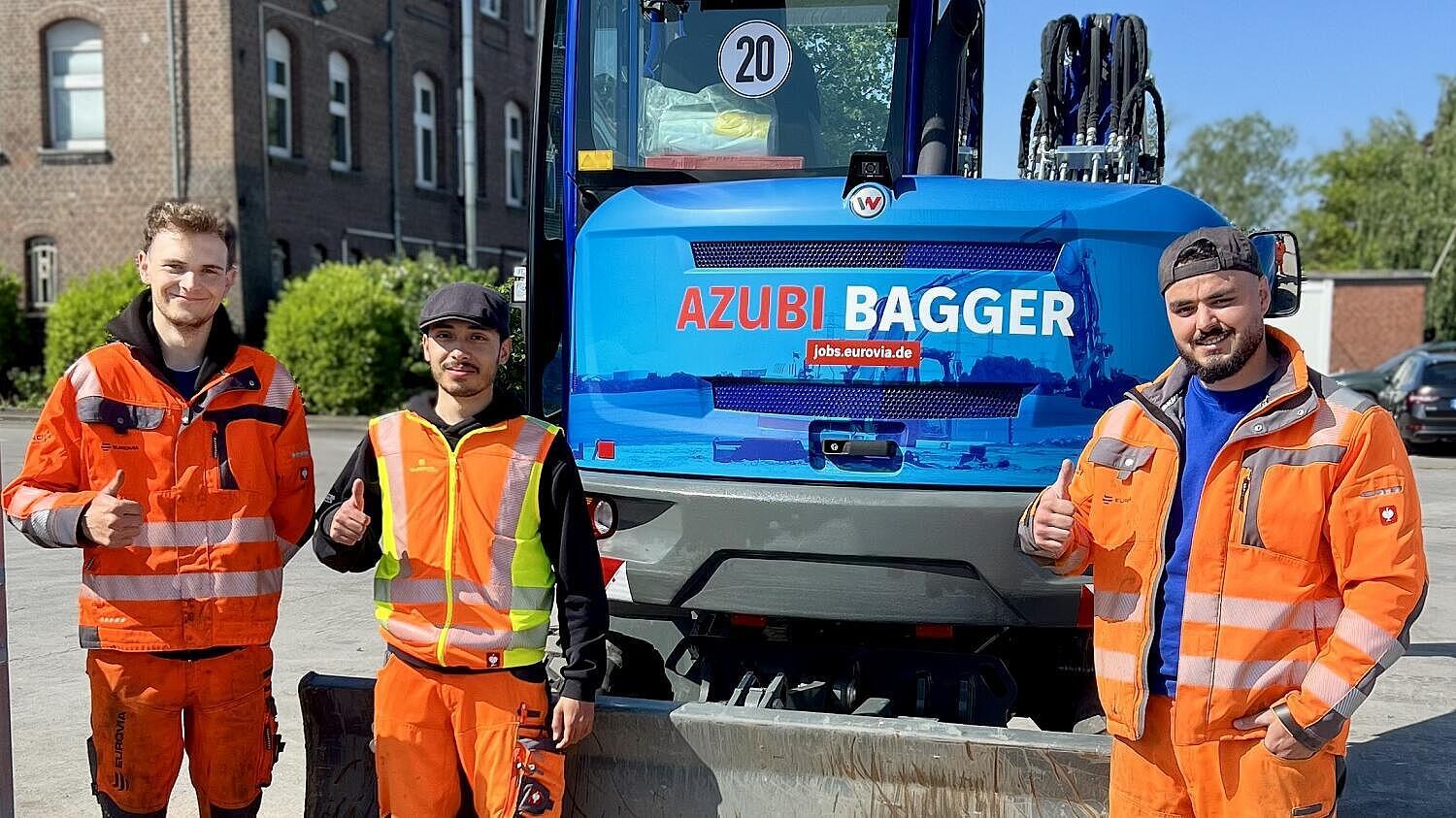 Bagger mit Auszubildenden im Vordergrund 