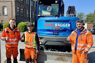 Bagger mit Auszubildenden im Vordergrund 