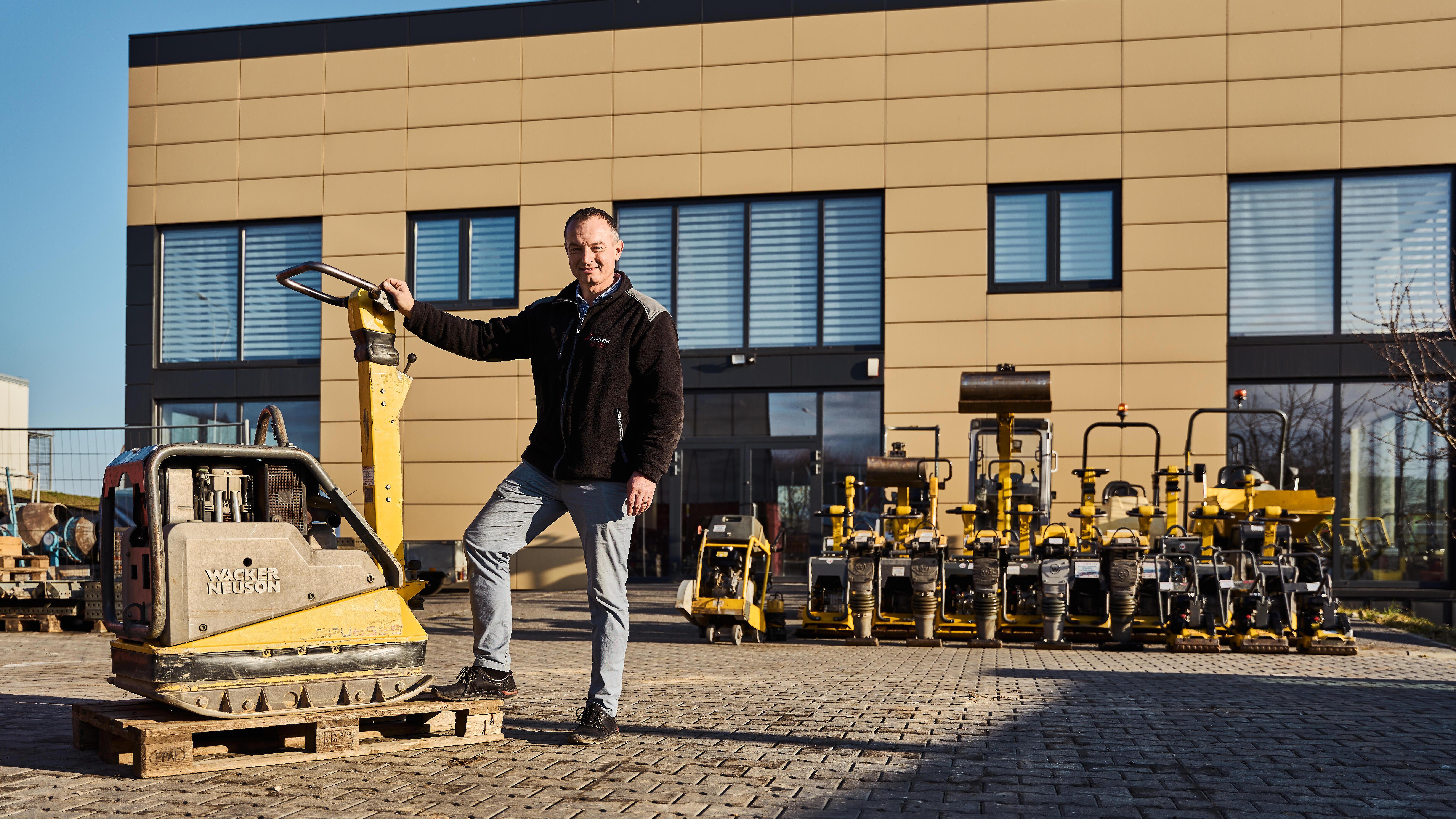 Wacker Neuson employee with vibratory plate in front of company building